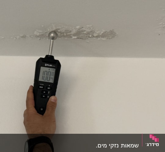 מד לחות נוגע בתקרה עם סימני רטיבות